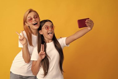 Mutlu anne ve kız akıllı telefondan selfie çekiyorlar.