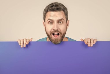 Reklam ve pazarlama için fotokopi alanı olan boş mavi pankartın arkasındaki olgun sakallı adam hayrete düştü.