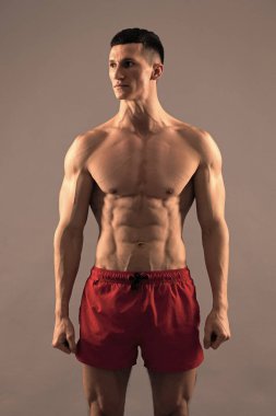 O iyi durumda. Spor şortlu tişörtsüz adam. Fit adam gri arkaplan. Sporcu adam.