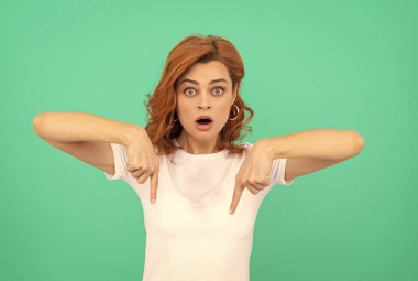 Şuraya bak. Şok olmuş kıvırcık saçlı, işaret parmağı aşağıda bir kadın. güzellik ve moda.