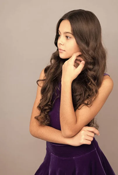 child portrait with long frizzy hair touch her face skin, beauty