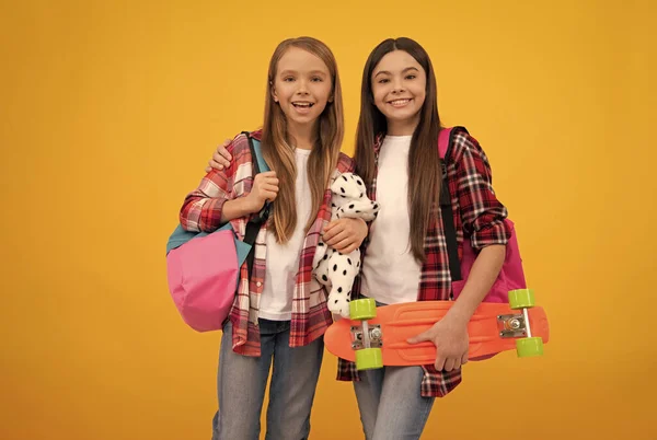 Niños felices en camisa a cuadros casuales llevan el juguete de la mochila y el tablero del centavo, estilo de vida casual —  Fotos de Stock