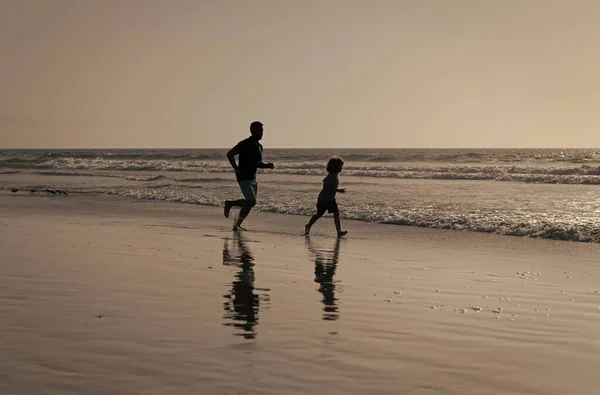 Ojciec i syn sylwetki działa zabawy i poczuć wolność na plaży letniej, dzieciństwo — Zdjęcie stockowe