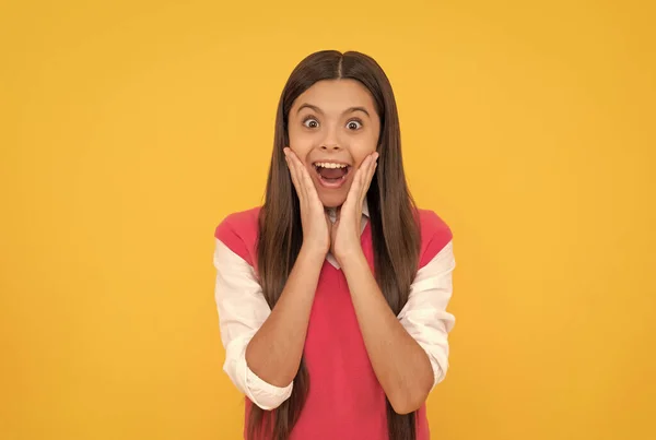 Zaskoczony nastolatek szkoła dziewczyna uśmiechnięta z długimi włosami na żółtym tle, niespodzianka — Zdjęcie stockowe