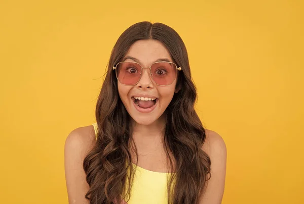 Stupito teen girl in occhiali estivi ha i capelli ricci su sfondo giallo, stupore e sorpresa — Foto Stock