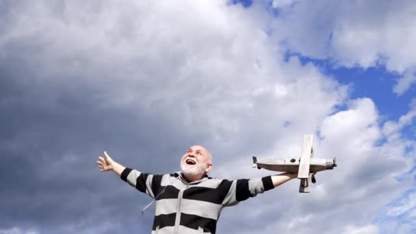 Gelukkig senior man doen alsof vliegen op houten vliegtuig in de lucht, vrijheid — Stockvideo