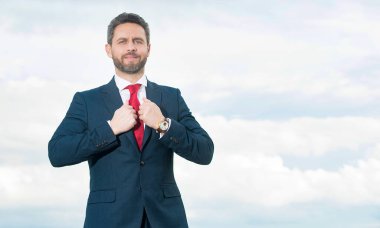 Gökyüzü arka planında iş adamı gibi gülümseyen bir iş adamı