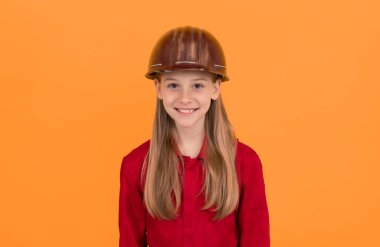 Turuncu arka planda miğferli mutlu çocuk.