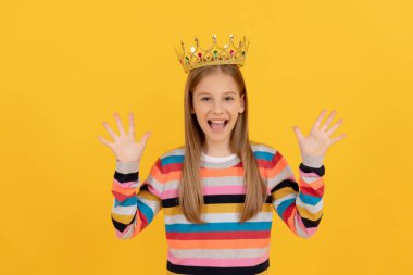 glad teen child in queen crown on yellow background