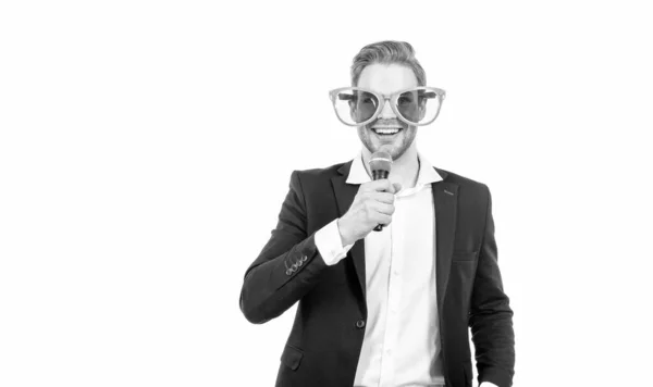 Hombre divertido en ropa formal de negocios y gafas de fiesta sostienen micrófono feliz sonriendo, showman — Foto de Stock