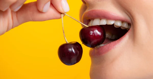 Womans enjoying fresh sweet cherry. Female mouth eating sweet cherry. Closeup female mouth tasting sweet cherry. Royalty Free Stock Images