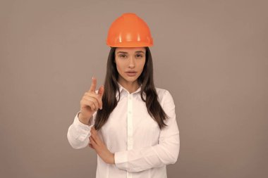 Koruyucu kasklı ve beyaz gömlekli ciddi kadın patron kamerayı işaret ediyor, kadın patron.