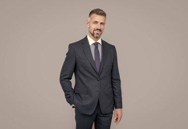 Gri saçlı, resmi takım elbiseli, karizmalı olgun bir lider.