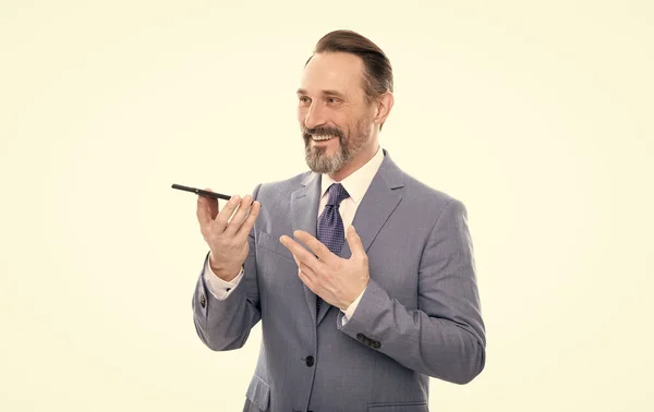 Sorridente uomo d'affari grizzled in tuta inviare messaggio vocale al telefono isolato su bianco, messaggio vocale. — Foto Stock