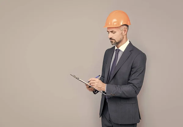 Deskundigheid op het gebied van veiligheid. Succesvolle man met een hoed die notities maakt. ondernemer lees project. — Stockfoto