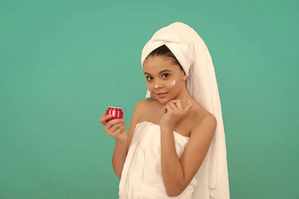 Presentatie cosmetische product voor tiener. Het kind gebruikt gezichtscrème. jong meisje houden haarmasker. — Stockfoto