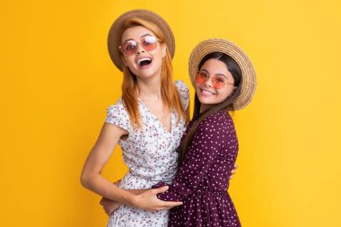 positive mother and child in straw hat on yellow background