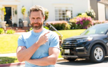 dealer man standing point finger on car and new house