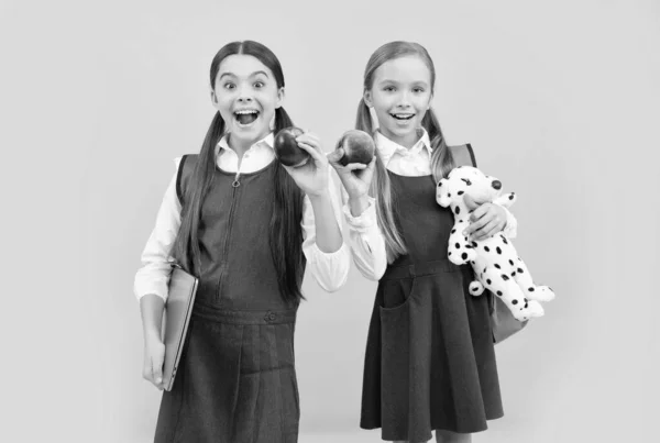 Los escolares en uniformes formales mantienen la boca abierta de sorpresa con manzanas naturales, alimentación saludable —  Fotos de Stock