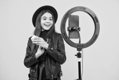 Neşeli çocuk makyaj yapar. Toz fırçalı vlogger. Telefonda video günlüğü oluşturuluyor.