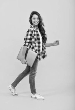 Bir sonraki seviye bir okul. Mutlu kız çocuğu dizüstü bilgisayar taşıyor. E-öğrenme kursu. Çevrim içi rota