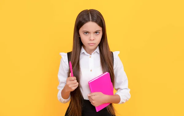 Serious frown child hold school book and pen yellow background, learning — Stockfoto