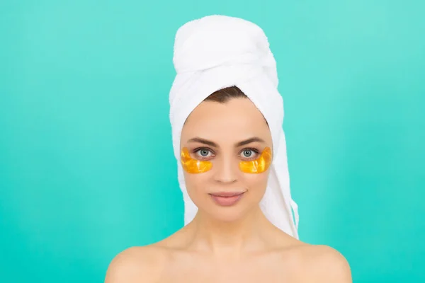 Girl has collagen golden eye patches on face with towel — Zdjęcie stockowe