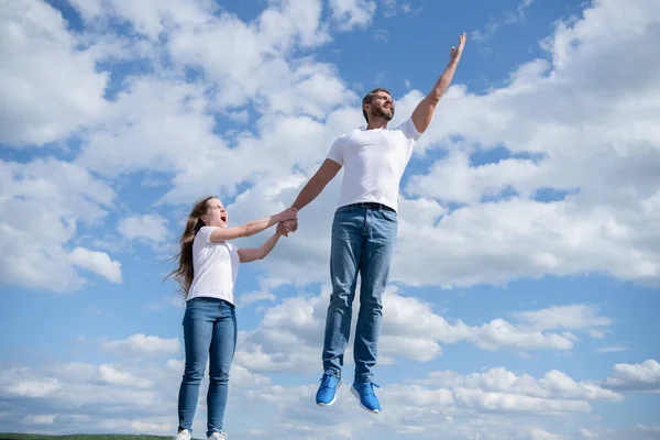 Daughter hold her dad jumping in sky — стоковое фото