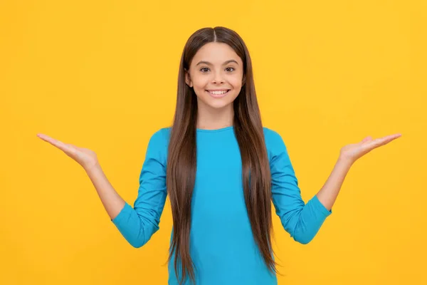 Happy teen girl with long hair making choice on yellow background with copy space, choice — ストック写真