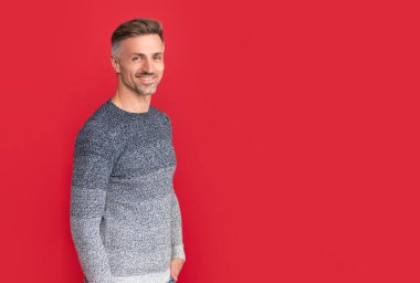 cheerful handsome man wear sweater on red background, lifestyle