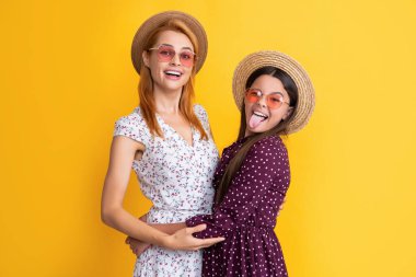 glad mom and daughter in straw hat on yellow background