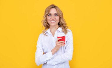 glad blonde woman with coffee cup on yellow background