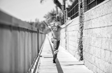 Aktif bir hayat yaşarken mutlu ve enerjik ol. Gezinti güvertesinde koşan enerjik bir çocuk. Eğlenceli çocukluk