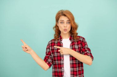 Mavi arka planda kareli gömlekli, kızıl saçlı, komik bir kadın.