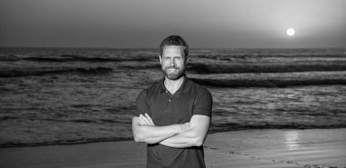 Güneşin doğuşunda, yaz kumsalında, tatilde neşeli bir adam.