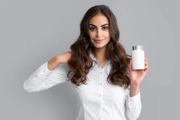 Woman with bottle pills. Happy young African American woman holding bottle of dietary supplements or vitamins in her hands. Healthy hair care concept.
