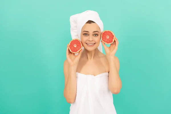 Gelukkige jonge vrouw in handdoek na douche met grapefruit op blauwe achtergrond. schoonheid — Stockfoto