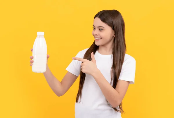 Cheerful child point finger on dairy beverage product. teen girl going to drink milk — Stok fotoğraf