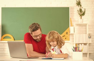 Öğretmen ve çocuk eğitimi sınıfta dizüstü bilgisayarla, babalıkla