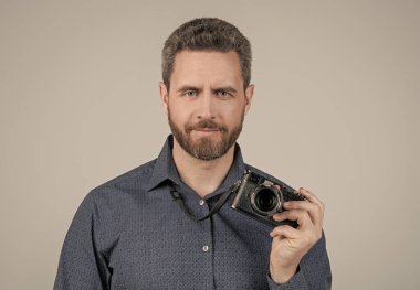 Günlük stilde sakallı adam. Fotoğraf makinesi, gri arka plan, kameraman.