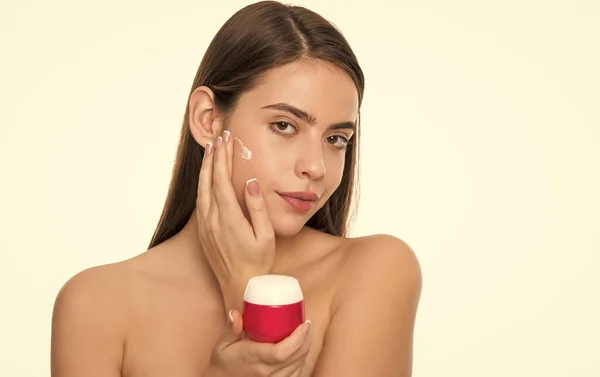 Giovane donna che applica crema per la pelle del viso isolata su sfondo bianco, abitudine quotidiana — Foto Stock