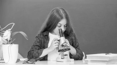 Mikroskobu olan çocuk karatahta, bilim sınıfında.