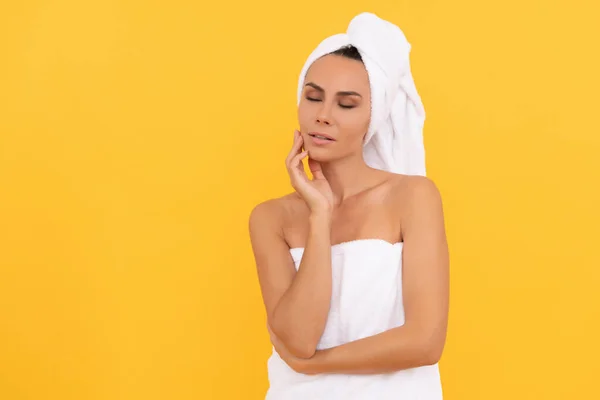 Young woman in towel after shower on yellow background with copy space — Stockfoto