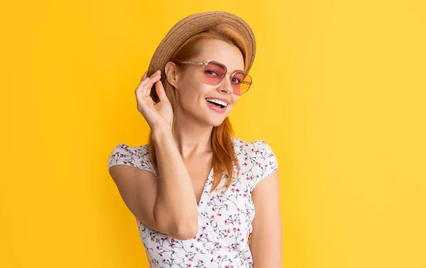 Весела молода жінка в солом'яному капелюсі і сонцезахисних окулярах на жовтому фоні — стокове фото