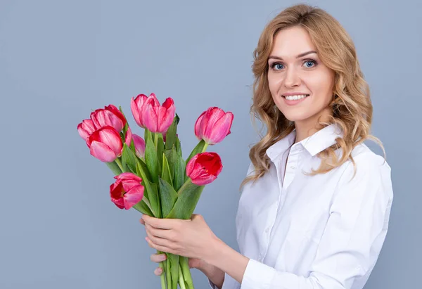 Gri arka planda bahar lale çiçekleri olan mutlu genç bir kadının yüzü — Stok fotoğraf