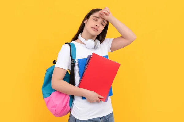 Vermoeide vrouw met oortjes houden notebook op gele achtergrond, terug naar school — Stockfoto