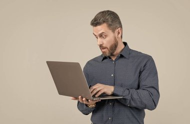 Şaşırtıcı, sakallı, yakışıklı, olgun iş adamı laptopta çalışıyor.