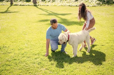 Evcil hayvanı olan arkadaş canlısı aile eğleniyor. Mutlu adam ve kadın köpekle oynuyorlar. Erkek ve kız birlikte rahatlar.