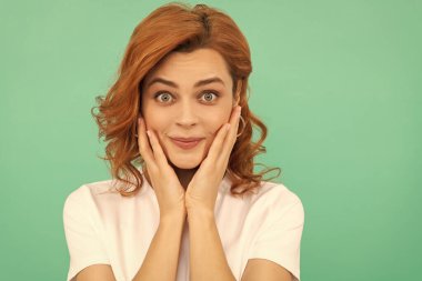 Harika bir teni ve mavi arka planda kıvırcık saçları olan, güzel bir portresi olan şaşkın bir kızıl kız.