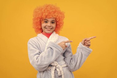 Süslü turuncu peruklu neşeli çocuk fotokopi odasında bornoz giyiyor, promosyon yapıyor.